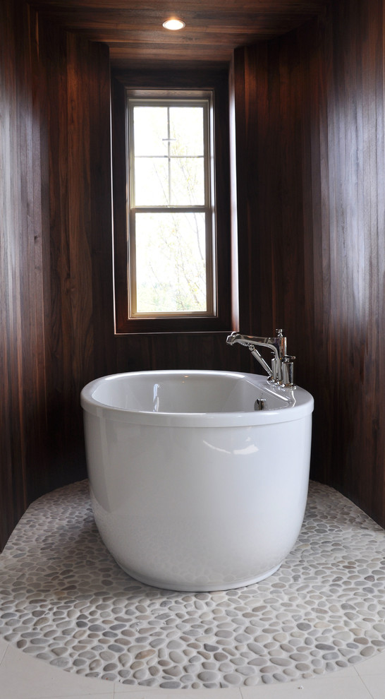 Idée de décoration pour une grande salle de bain principale minimaliste avec une baignoire indépendante, un carrelage blanc, une plaque de galets, un mur gris et un sol en carrelage de porcelaine.