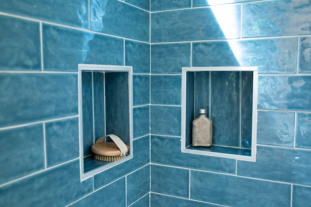 Maritim inredning av ett litet beige beige badrum med dusch, med öppna hyllor, beige skåp, en hörndusch, en toalettstol med hel cisternkåpa, blå kakel, keramikplattor, beige väggar, laminatgolv, ett fristående handfat, träbänkskiva, beiget golv och dusch med skjutdörr