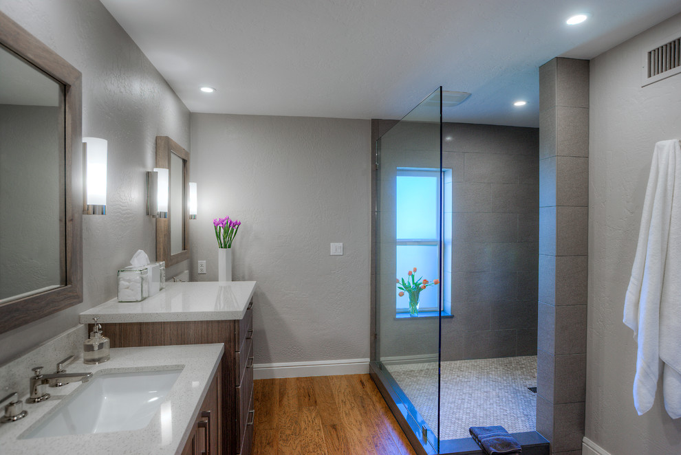 Inspiration for a small contemporary master gray tile and porcelain tile medium tone wood floor and brown floor double shower remodel in Phoenix with an undermount sink, quartzite countertops, gray walls, medium tone wood cabinets, shaker cabinets, a one-piece toilet and a hinged shower door