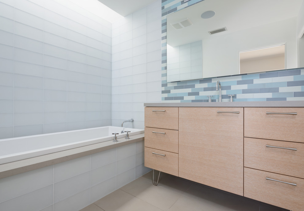 Idéer för ett mellanstort 60 tals badrum med dusch, med släta luckor, skåp i ljust trä, ett badkar i en alkov, en dusch/badkar-kombination, blå kakel, stickkakel och ett undermonterad handfat
