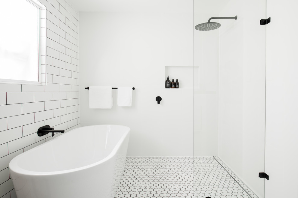 Foto på ett maritimt badrum, med ett fristående badkar, en kantlös dusch, vit kakel, tunnelbanekakel, vita väggar, mosaikgolv, vitt golv och med dusch som är öppen