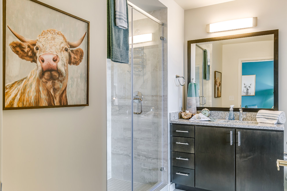 Inspiration for a small traditional bathroom in Dallas with flat-panel cabinets, dark wood cabinets, an alcove shower, a one-piece toilet, grey tiles, porcelain tiles, beige walls, medium hardwood flooring, a built-in sink, granite worktops, brown floors and a hinged door.