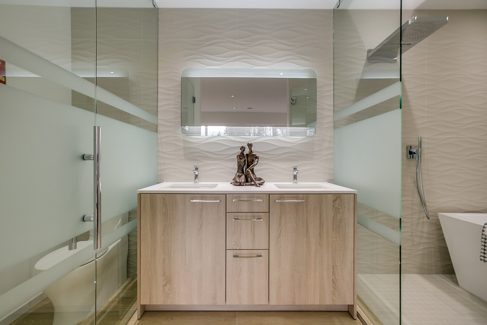 Modern inredning av ett mellanstort en-suite badrum, med ett undermonterad handfat, släta luckor, skåp i ljust trä, ett fristående badkar, en toalettstol med separat cisternkåpa, vita väggar, en öppen dusch, beige kakel, porslinskakel, bänkskiva i akrylsten och med dusch som är öppen