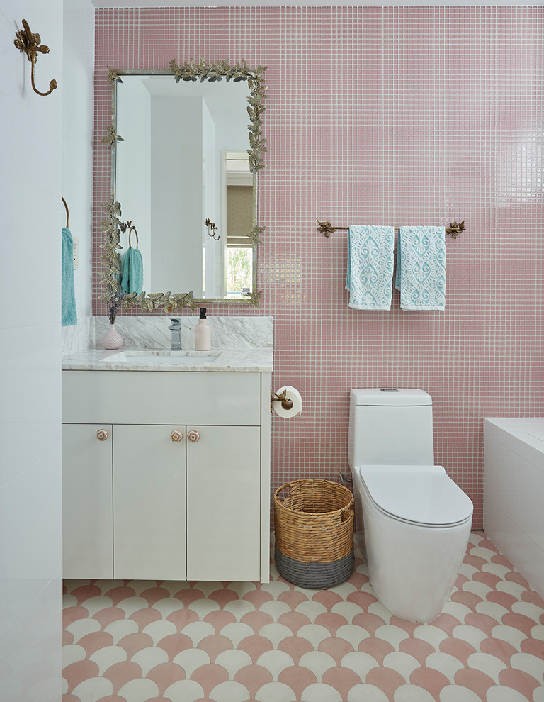 シンガポールにあるトランジショナルスタイルのおしゃれな子供用バスルーム (フラットパネル扉のキャビネット、白いキャビネット、ピンクのタイル、ピンクの壁、アンダーカウンター洗面器、ピンクの床、グレーの洗面カウンター) の写真