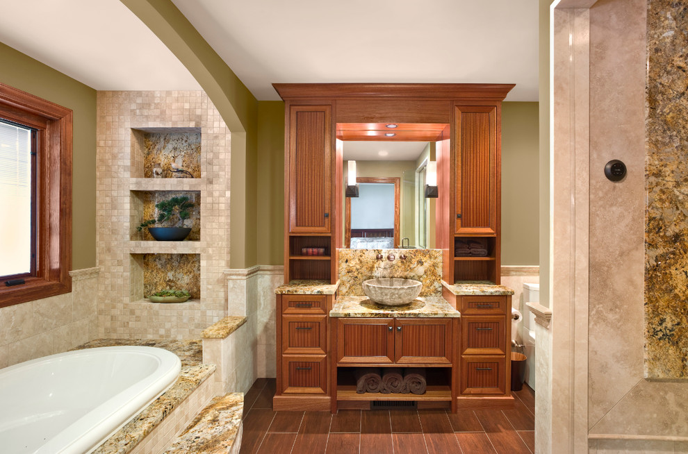 Exempel på ett mellanstort medelhavsstil en-suite badrum, med ett fristående handfat, skåp i mellenmörkt trä, ett platsbyggt badkar, beige kakel, granitbänkskiva, stenhäll, en öppen dusch, en toalettstol med hel cisternkåpa, gröna väggar, klinkergolv i keramik och luckor med infälld panel