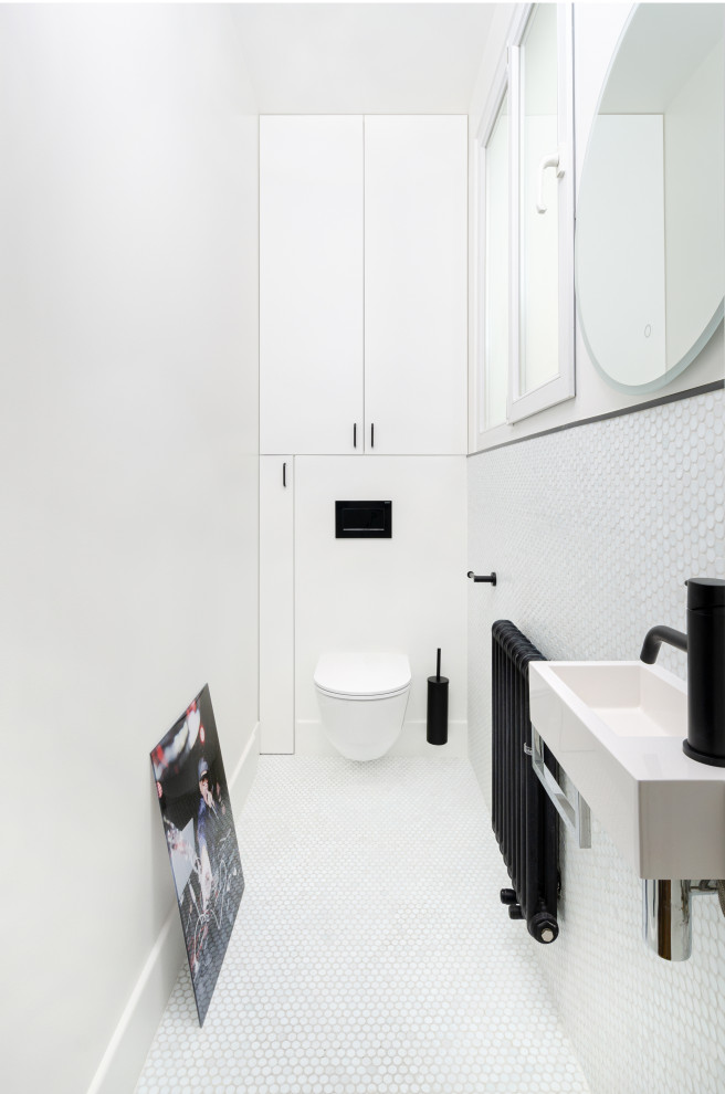Imagen de cuarto de baño principal contemporáneo pequeño con armarios con paneles empotrados, puertas de armario blancas, sanitario de pared, baldosas y/o azulejos blancos, paredes blancas y lavabo suspendido