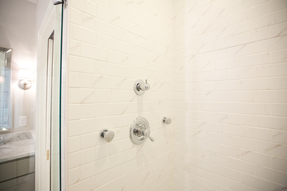 Réalisation d'une salle de bain principale tradition de taille moyenne avec un placard à porte shaker, des portes de placard grises, un carrelage blanc, du carrelage en marbre, un mur blanc, un lavabo encastré et un plan de toilette en marbre.