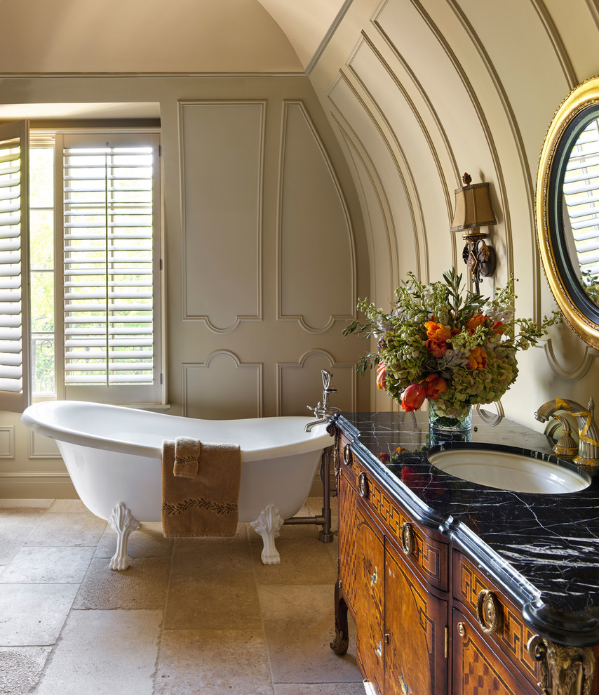 Inredning av ett klassiskt svart svart en-suite badrum, med skåp i mellenmörkt trä, ett badkar med tassar, beige väggar, ett undermonterad handfat, marmorbänkskiva, beiget golv och släta luckor