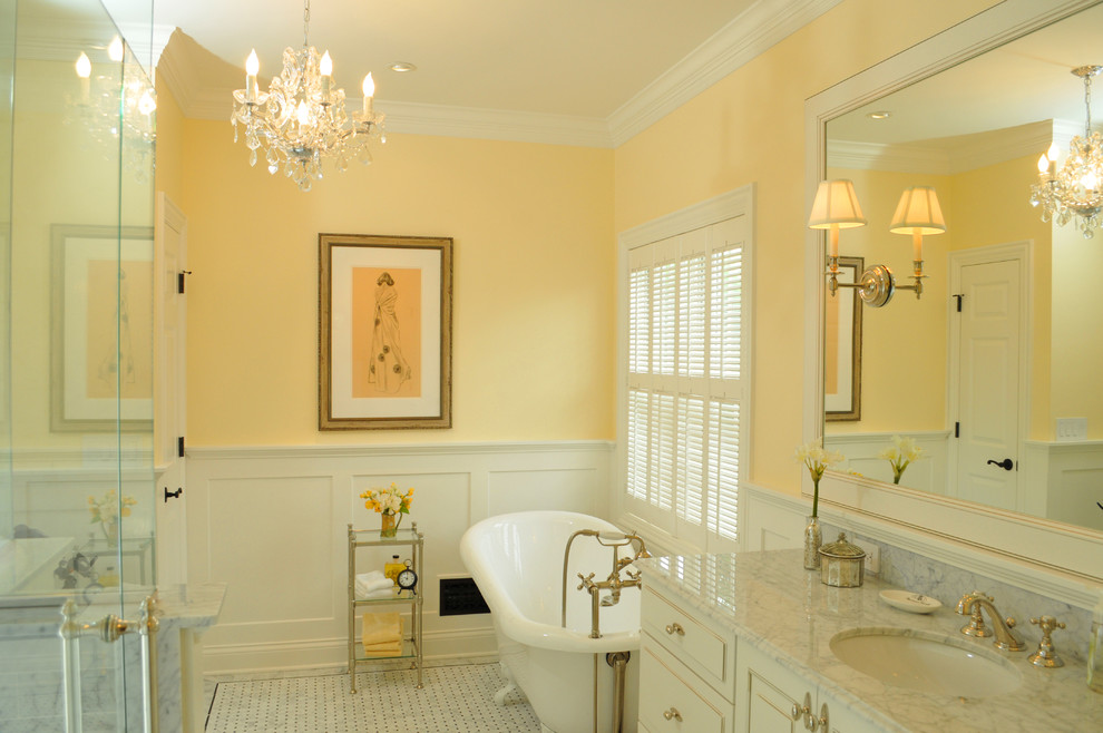 Пример оригинального дизайна: главная ванная комната в классическом стиле с фасадами островного типа, белыми фасадами, ванной на ножках, белой плиткой, каменной плиткой, желтыми стенами, полом из мозаичной плитки и мраморной столешницей