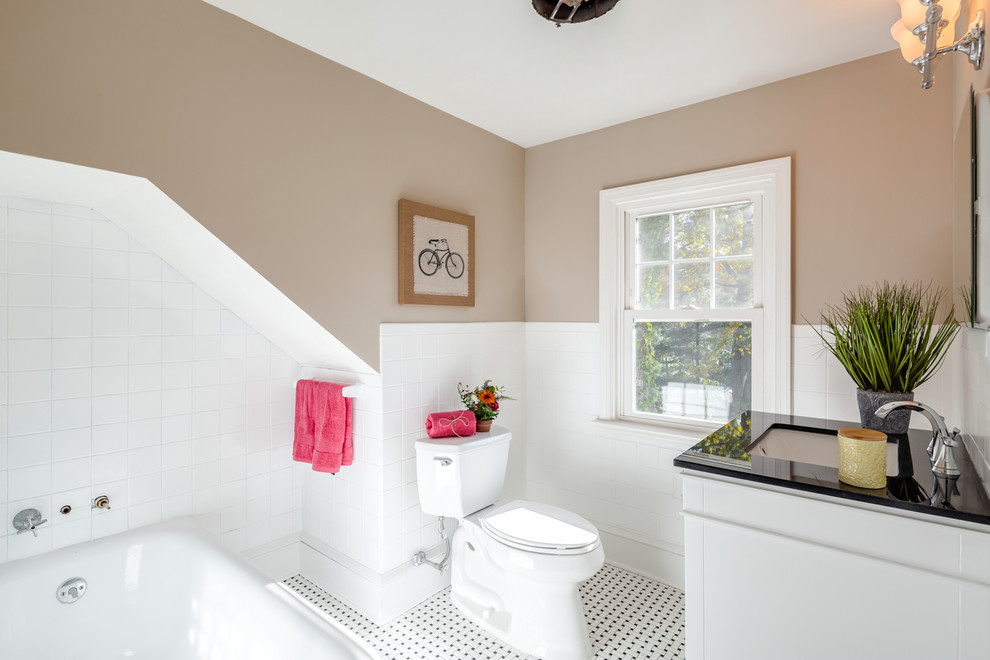 На фото: ванная комната в классическом стиле с белыми фасадами, ванной в нише, белой плиткой, коричневыми стенами, полом из мозаичной плитки, врезной раковиной и черной столешницей