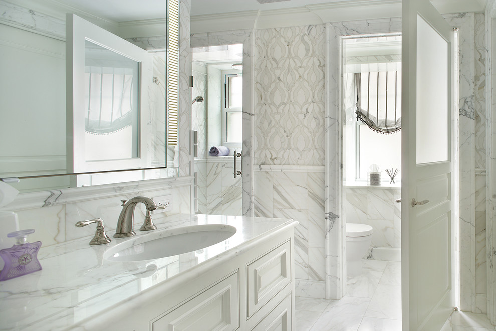 Immagine di una stanza da bagno padronale chic di medie dimensioni con ante con bugna sagomata, ante bianche, piastrelle bianche, lastra di pietra, pareti bianche, pavimento in marmo, lavabo sottopiano, top in marmo e pavimento bianco