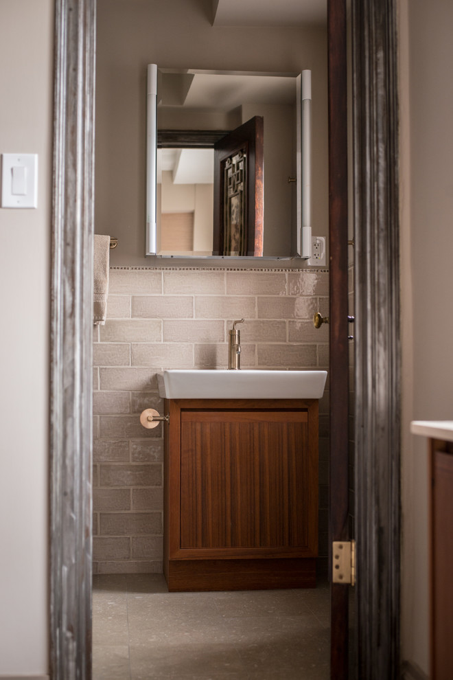 Cette image montre une petite salle de bain principale vintage en bois brun avec un lavabo suspendu, un placard en trompe-l'oeil, une baignoire en alcôve, un carrelage gris, des carreaux de céramique, un mur gris et un sol en travertin.