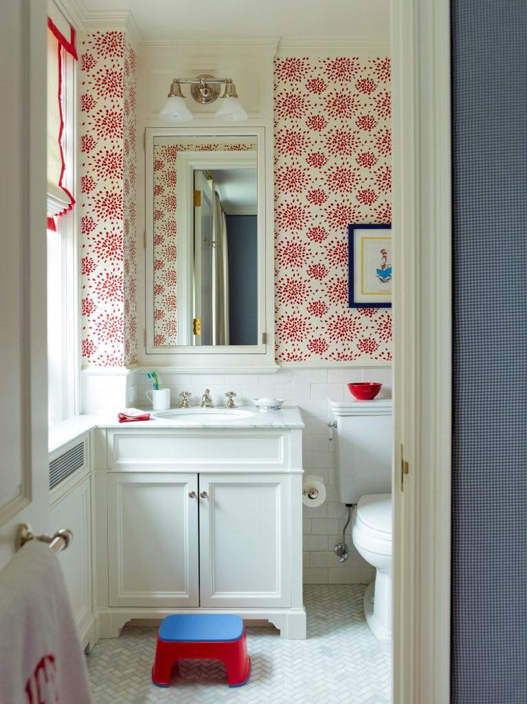 Klassisk inredning av ett litet badrum för barn, med ett undermonterad handfat, vita skåp, marmorbänkskiva, en dusch/badkar-kombination, en toalettstol med separat cisternkåpa, flerfärgade väggar, marmorgolv, luckor med infälld panel och vit kakel