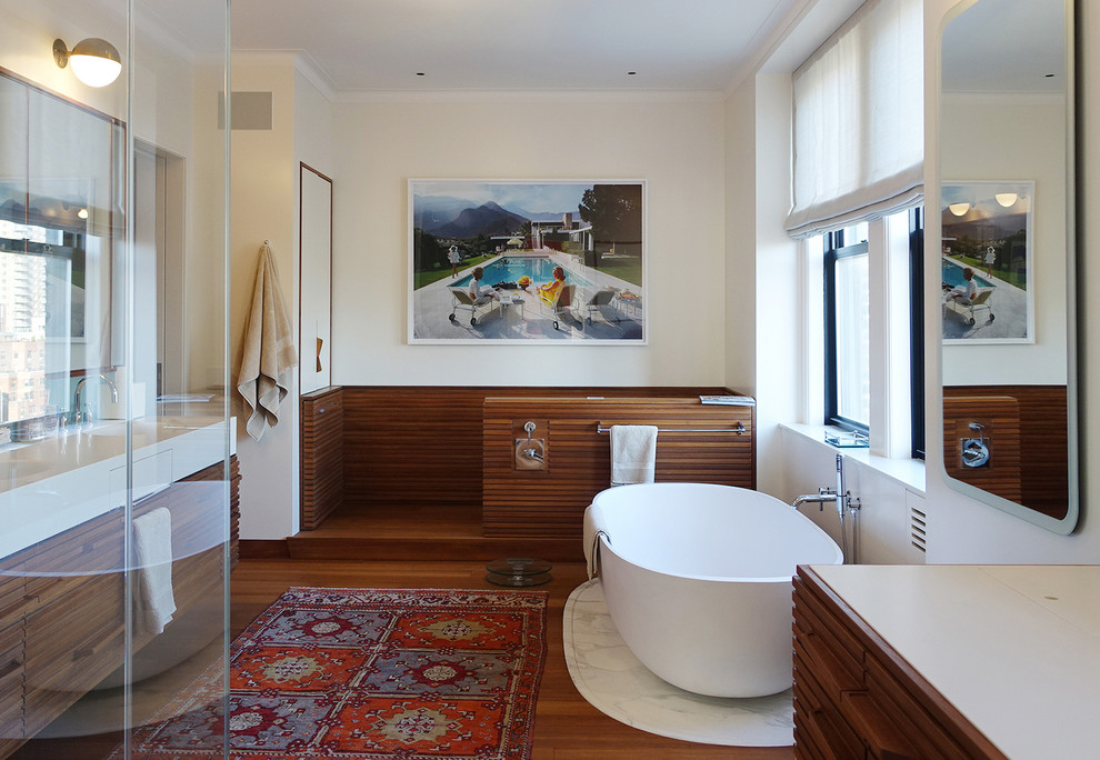 Réalisation d'une grande salle de bain principale design avec un mur blanc, une baignoire indépendante, un sol en bois brun et une fenêtre.