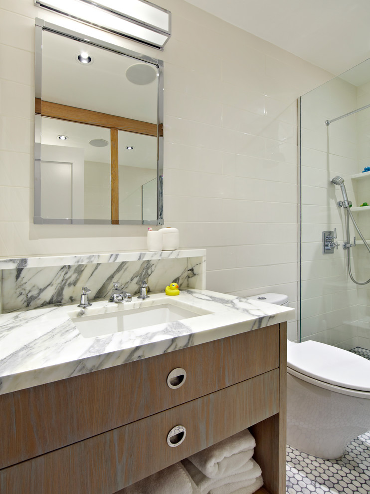 Idée de décoration pour une salle de bain design en bois clair avec un placard à porte plane, WC à poser, un mur blanc et un lavabo encastré.