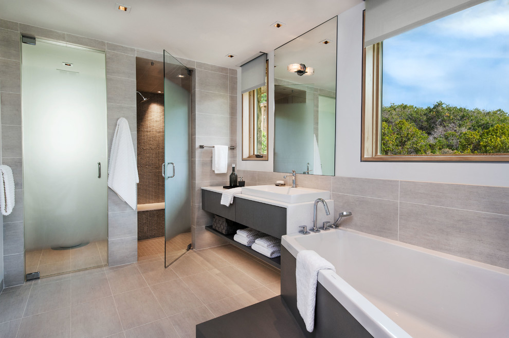 Bild på ett funkis en-suite badrum, med ett fristående handfat, släta luckor, grå skåp, ett hörnbadkar, en kantlös dusch, grå kakel och vita väggar