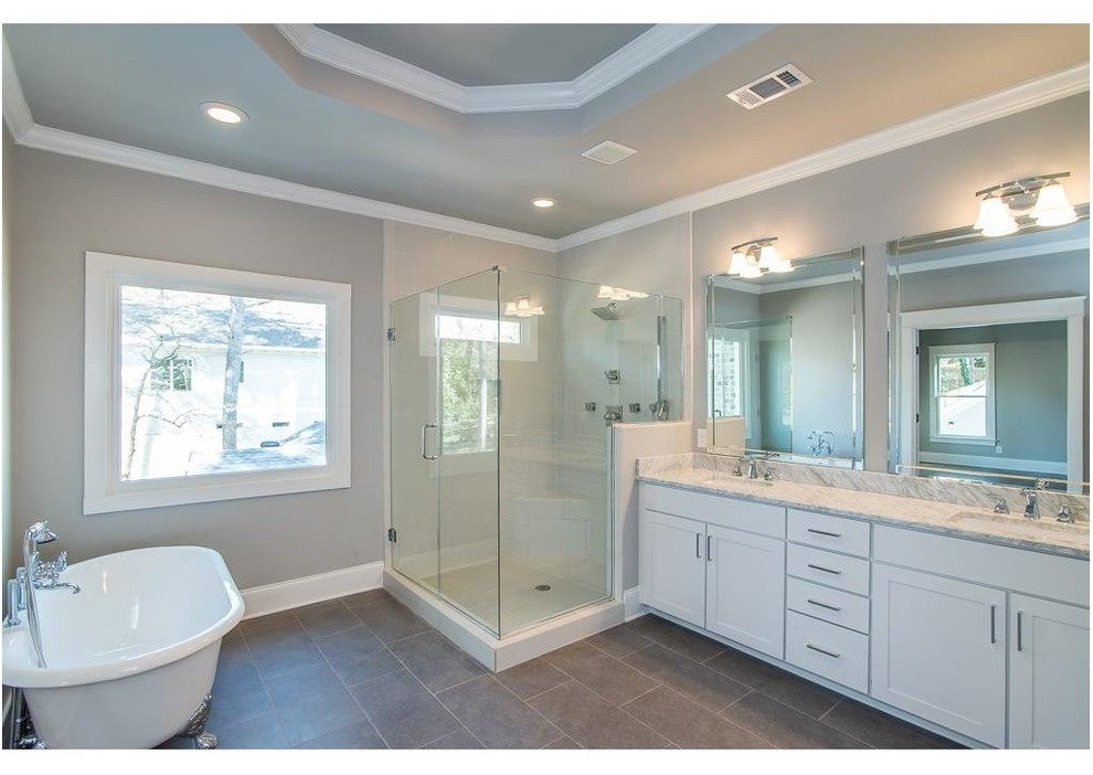 Aménagement d'une salle de bain craftsman avec une baignoire sur pieds, un carrelage gris et un mur gris.