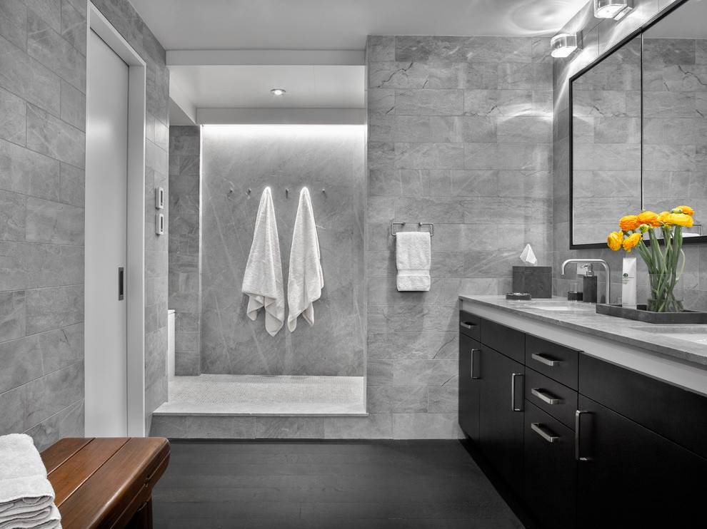 Doorless shower - modern master gray tile and stone tile dark wood floor doorless shower idea in New York with flat-panel cabinets, dark wood cabinets, a wall-mount toilet, gray walls, an undermount sink and marble countertops