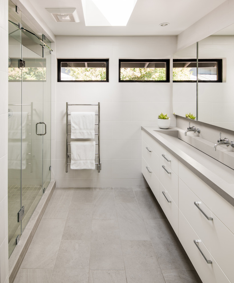 Medium sized modern family bathroom in San Francisco with flat-panel cabinets, white cabinets, a walk-in shower, a one-piece toilet, white tiles, porcelain tiles, white walls, travertine flooring, an integrated sink, engineered stone worktops, grey floors, a hinged door and grey worktops.