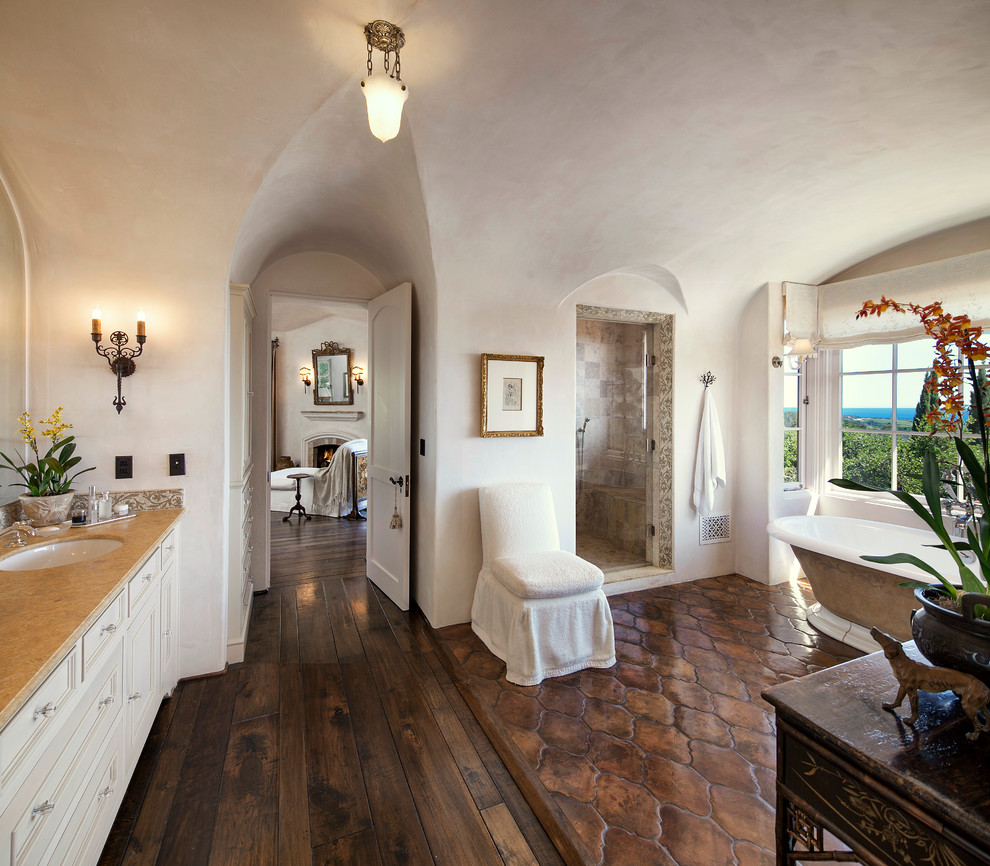 Стильный дизайн: главная ванная комната в средиземноморском стиле с врезной раковиной, белыми фасадами, отдельно стоящей ванной, душем в нише, коричневой плиткой и темным паркетным полом - последний тренд