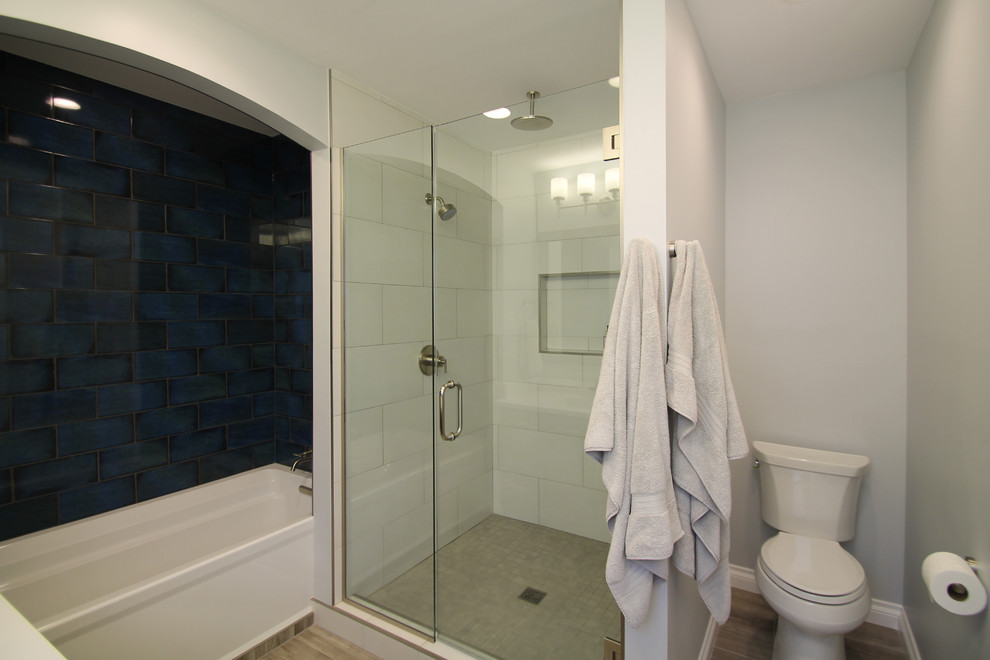 Exempel på ett stort klassiskt en-suite badrum, med släta luckor, skåp i mörkt trä, ett badkar i en alkov, en dusch/badkar-kombination, en toalettstol med separat cisternkåpa, vit kakel, porslinskakel, blå väggar, klinkergolv i porslin, ett undermonterad handfat och bänkskiva i kvarts