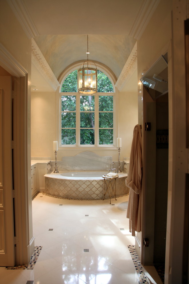 Exemple d'une grande salle de bain principale méditerranéenne avec une baignoire encastrée, un mur beige, un sol en marbre, un sol blanc, un placard avec porte à panneau encastré, des portes de placard beiges, un plan de toilette en marbre, un plan de toilette beige, meuble simple vasque, meuble-lavabo encastré et un plafond voûté.
