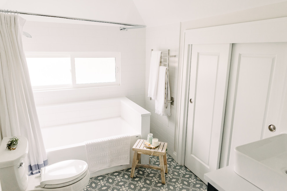 Идея дизайна: ванная комната среднего размера в стиле неоклассика (современная классика) с фасадами островного типа, синими фасадами, ванной в нише, душем над ванной, белой плиткой, плиткой кабанчик, белыми стенами, полом из цементной плитки, душевой кабиной, настольной раковиной, столешницей из искусственного камня, синим полом, шторкой для ванной и белой столешницей