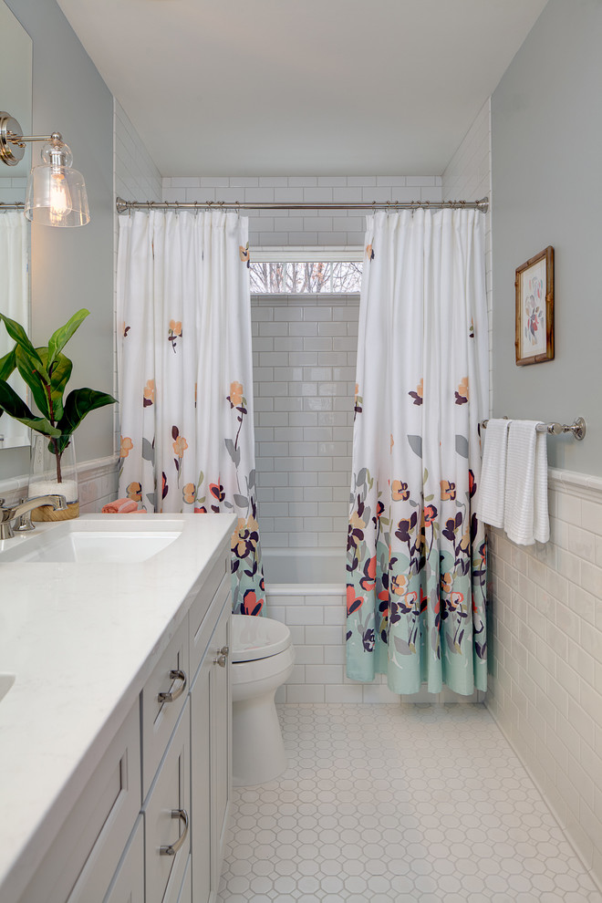 Bild på ett vintage badrum, med luckor med infälld panel, ett badkar i en alkov, en dusch/badkar-kombination, vit kakel, tunnelbanekakel, grå väggar, mosaikgolv och ett undermonterad handfat