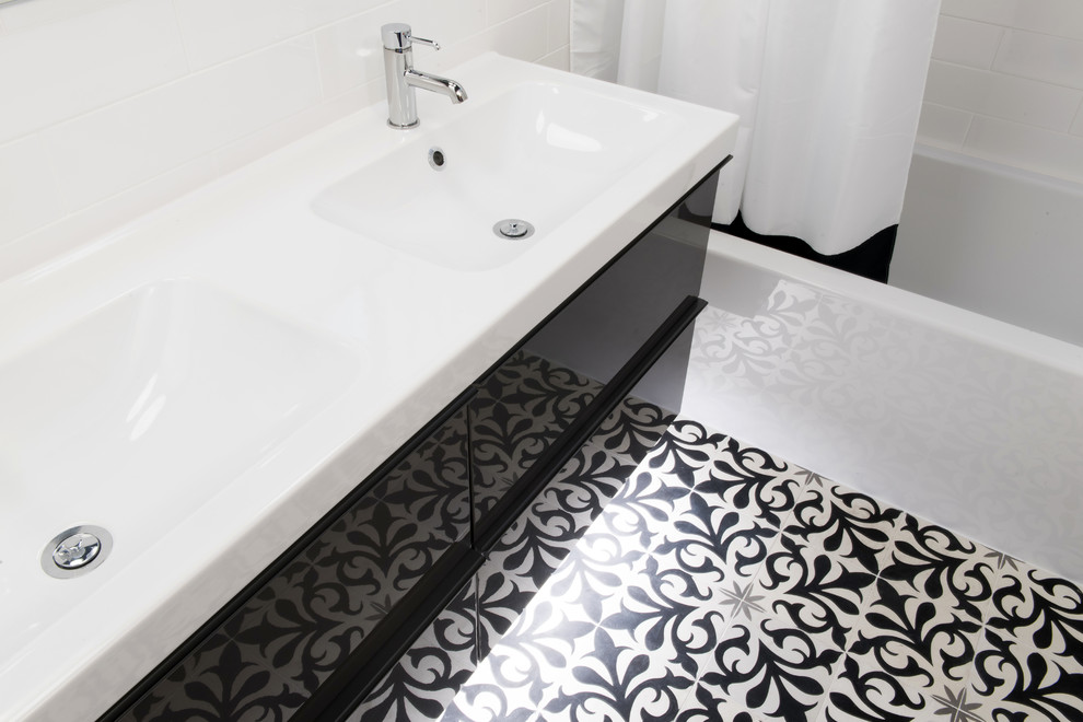 Exempel på ett 50 tals en-suite badrum, med släta luckor, svarta skåp, ett badkar i en alkov, en dusch/badkar-kombination, svart och vit kakel, porslinskakel, vita väggar, klinkergolv i porslin, ett integrerad handfat, bänkskiva i akrylsten och en toalettstol med separat cisternkåpa