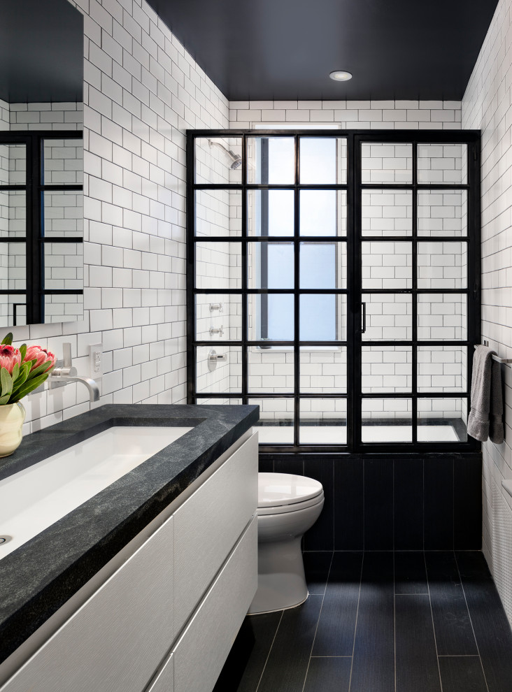 На фото: ванная комната в современном стиле с ванной в нише, душем над ванной, белой плиткой, плиткой кабанчик, черными стенами, душем с распашными дверями и черной столешницей с