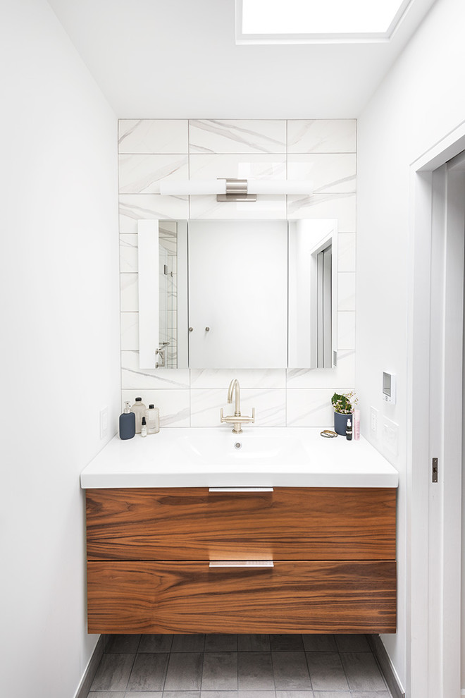 ニューヨークにある小さなコンテンポラリースタイルのおしゃれなバスルーム (浴槽なし) (フラットパネル扉のキャビネット、中間色木目調キャビネット、白いタイル、白い壁、一体型シンク、グレーの床) の写真