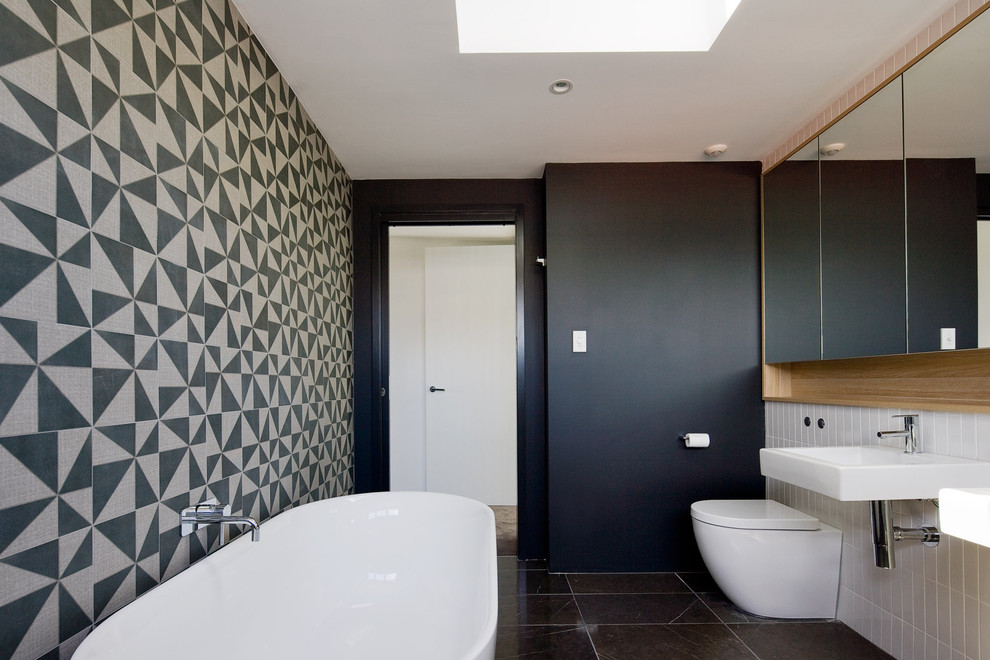 Inspiration for a contemporary black and white tile freestanding bathtub remodel in Sydney with a wall-mount sink and a one-piece toilet