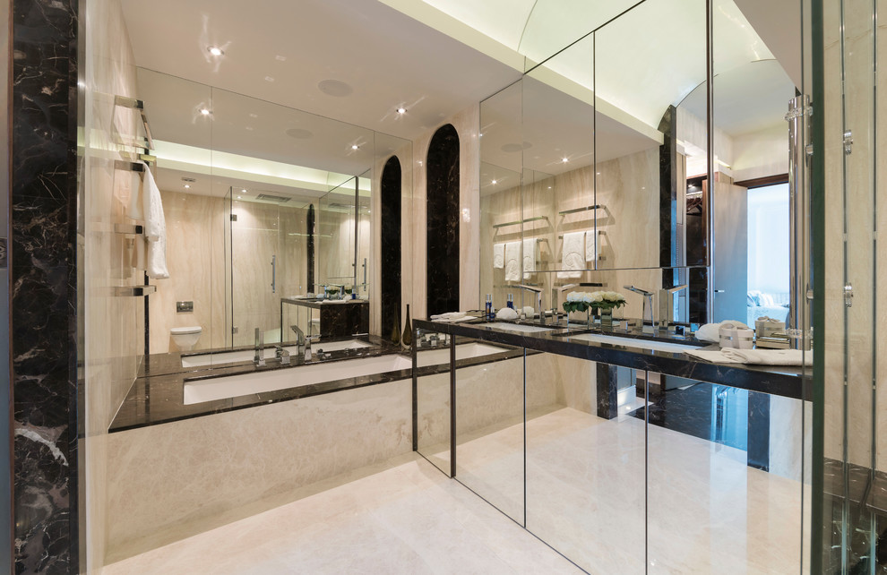 Large contemporary ensuite bathroom in London with a walk-in shower, a wall mounted toilet, beige tiles, beige walls, marble flooring, a built-in sink, marble worktops and a submerged bath.