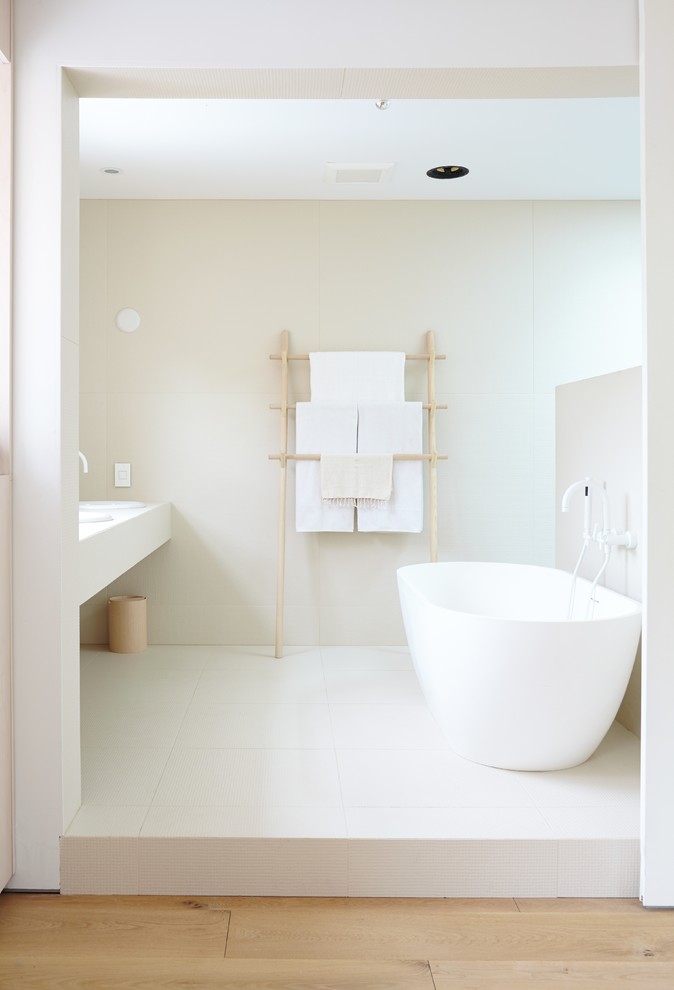 Exempel på ett stort modernt en-suite badrum, med ett undermonterad handfat, släta luckor, skåp i ljust trä, ett fristående badkar, en dusch i en alkov, en vägghängd toalettstol, beige kakel, porslinskakel, vita väggar och ljust trägolv