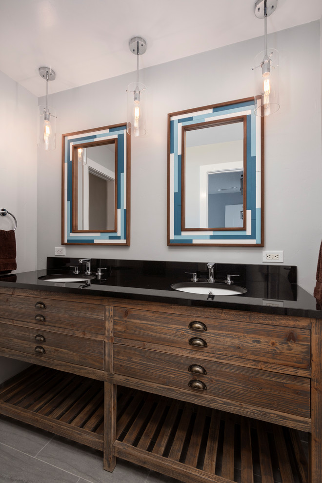 Medium sized contemporary bathroom in San Francisco with freestanding cabinets, distressed cabinets, an alcove bath, a shower/bath combination, a two-piece toilet, brown tiles, porcelain tiles, grey walls, porcelain flooring, a submerged sink, granite worktops, grey floors, a sliding door and black worktops.