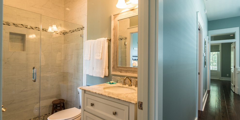 Bild på ett mellanstort vintage badrum med dusch, med luckor med infälld panel, vita skåp, en dusch i en alkov, en toalettstol med separat cisternkåpa, vit kakel, gröna väggar, ett undermonterad handfat och marmorbänkskiva