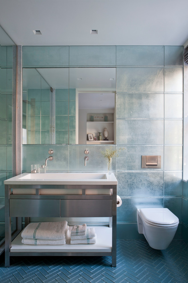 Bild på ett mellanstort funkis badrum med dusch, med marmorbänkskiva, blå kakel, glaskakel, släta luckor, en vägghängd toalettstol, blå väggar, ett integrerad handfat och blått golv