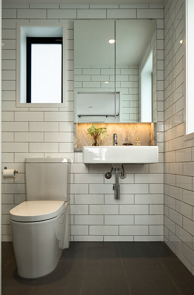 Пример оригинального дизайна: маленькая главная ванная комната в стиле модернизм с стеклянными фасадами, белыми фасадами, угловым душем, унитазом-моноблоком, белой плиткой, керамической плиткой, белыми стенами, полом из керамической плитки, подвесной раковиной, столешницей из гранита, серым полом и душем с распашными дверями для на участке и в саду