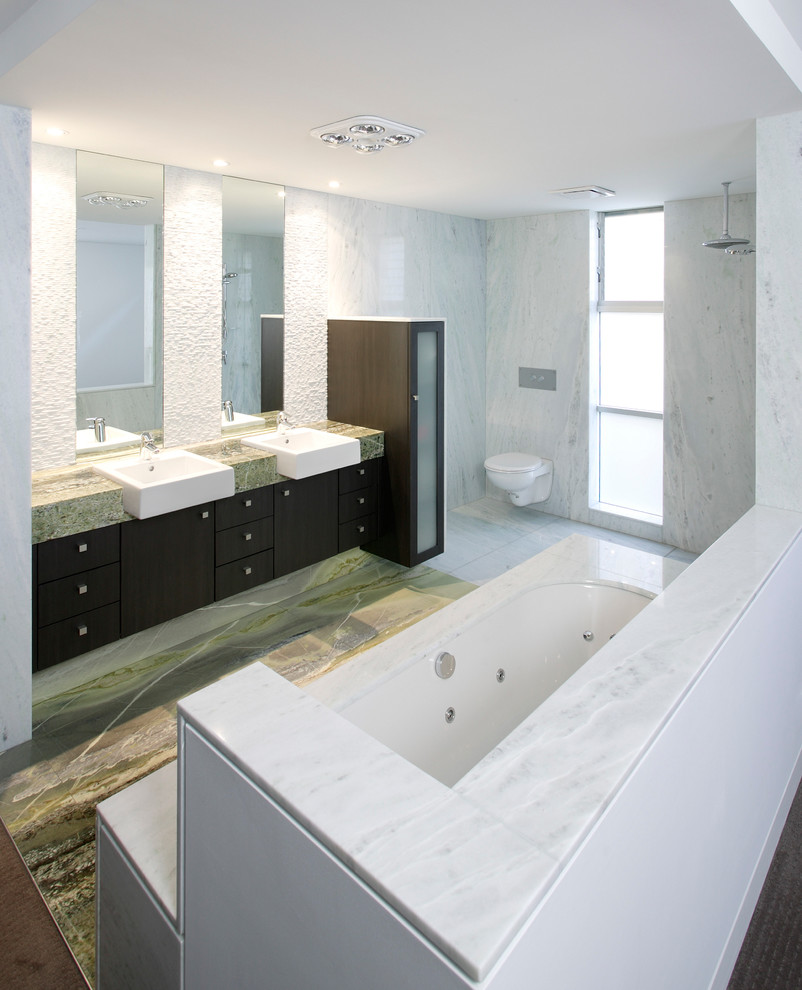 Свежая идея для дизайна: главная ванная комната с монолитной раковиной, плоскими фасадами, темными деревянными фасадами, мраморной столешницей, белой плиткой, белыми стенами, накладной ванной, открытым душем, унитазом-моноблоком и стеклянной плиткой - отличное фото интерьера