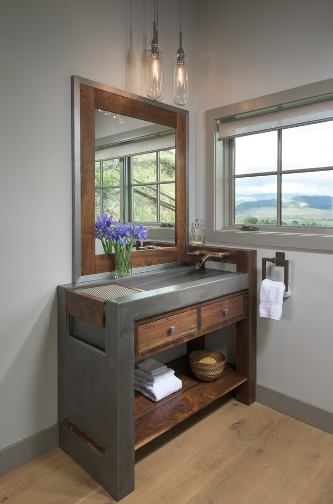 Ejemplo de cuarto de baño campestre de tamaño medio con armarios abiertos, puertas de armario de madera en tonos medios, encimera de cemento, paredes grises y suelo de madera clara