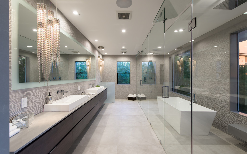 Modern inredning av ett grå grått en-suite badrum, med släta luckor, skåp i mörkt trä, ett fristående badkar, våtrum, grå väggar, ett fristående handfat, grått golv och dusch med gångjärnsdörr