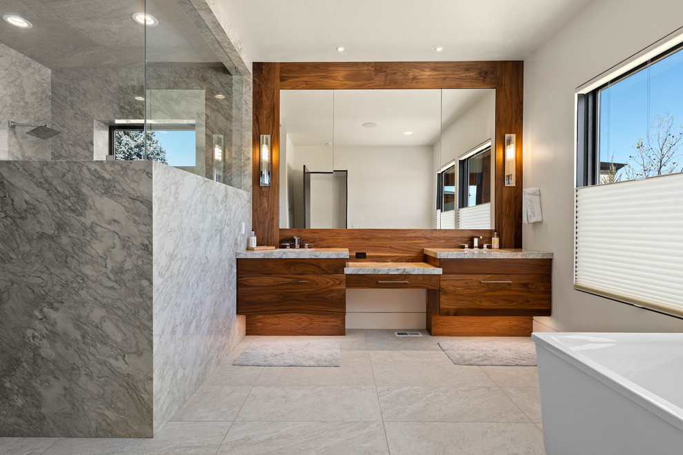 Réalisation d'une salle de bain principale design en bois brun avec une baignoire indépendante, une douche double, un carrelage blanc, des dalles de pierre, un mur blanc, un sol en carrelage de céramique, un lavabo encastré, un plan de toilette en quartz, un sol gris, une cabine de douche à porte battante et un plan de toilette gris.