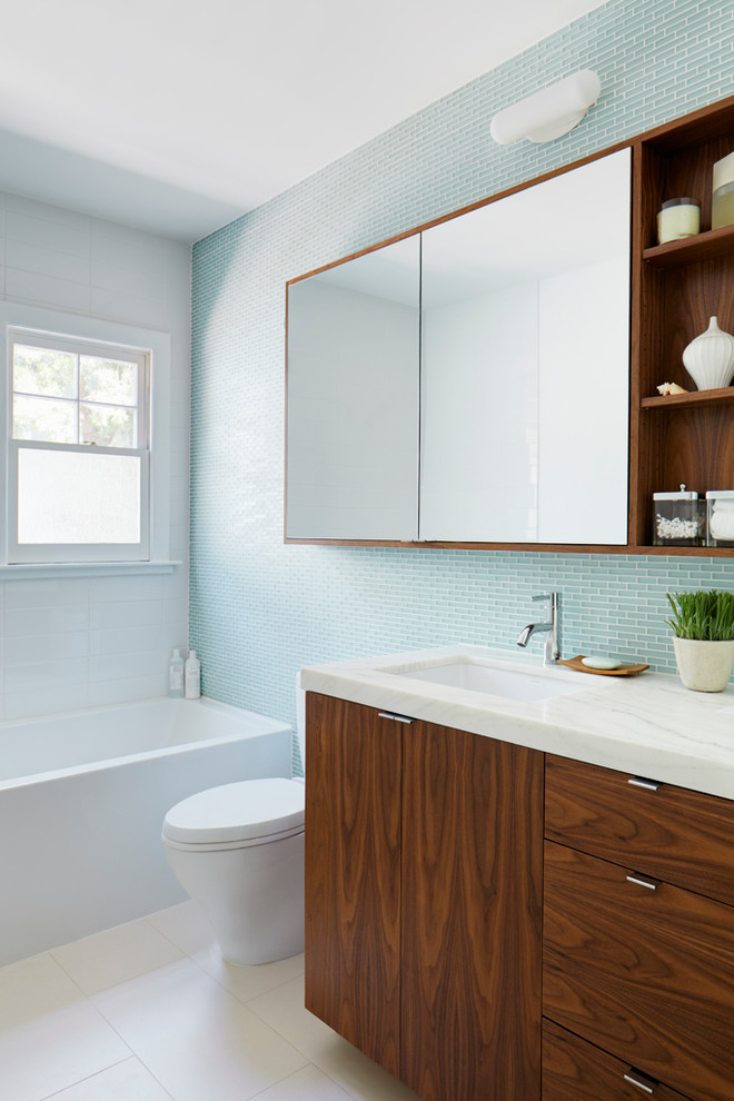 Ejemplo de cuarto de baño contemporáneo con armarios con paneles lisos, puertas de armario de madera en tonos medios, baldosas y/o azulejos azules y baldosas y/o azulejos de vidrio