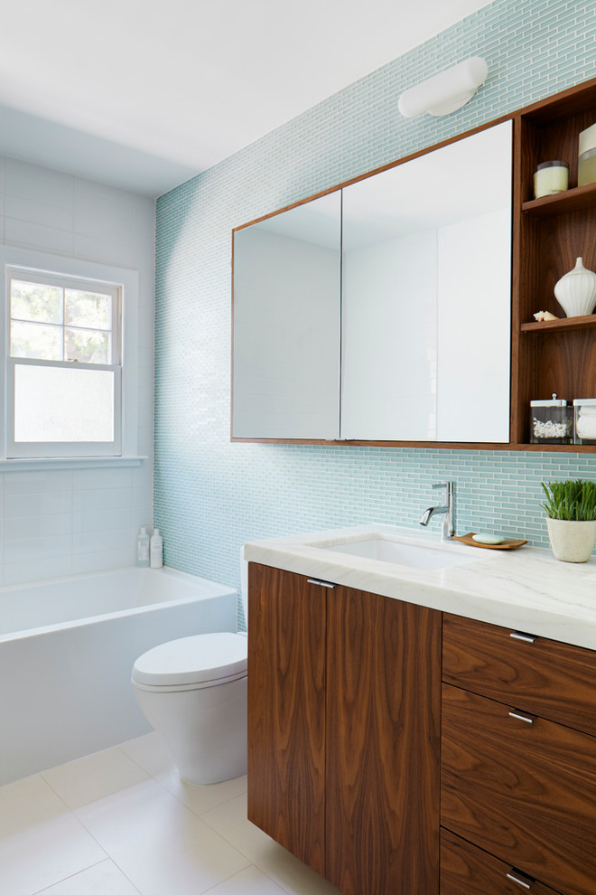 На фото: ванная комната в современном стиле с плоскими фасадами, темными деревянными фасадами, синей плиткой и стеклянной плиткой с