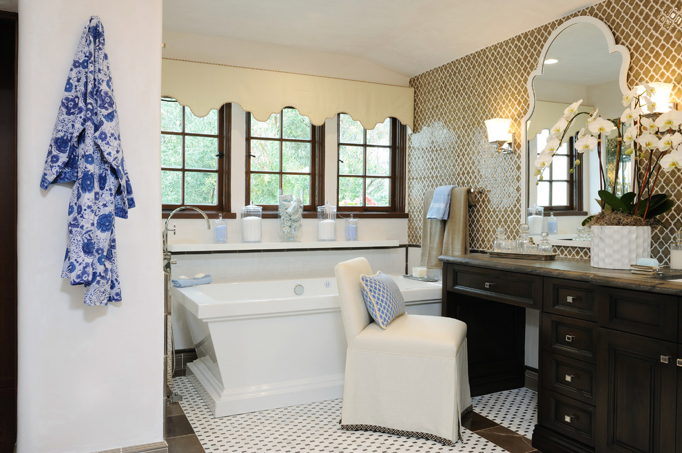 Свежая идея для дизайна: ванная комната в средиземноморском стиле с фасадами с утопленной филенкой, темными деревянными фасадами, отдельно стоящей ванной и бежевой плиткой - отличное фото интерьера