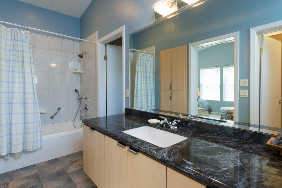 Idéer för att renovera ett mellanstort maritimt en-suite badrum, med ett undermonterad handfat, släta luckor, skåp i ljust trä, granitbänkskiva, ett badkar i en alkov, en dusch/badkar-kombination, en toalettstol med hel cisternkåpa, vit kakel, porslinskakel, blå väggar och travertin golv