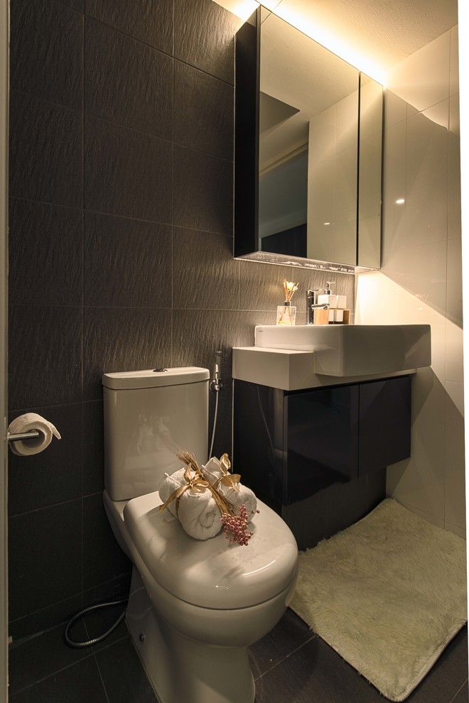 シンガポールにある低価格の小さな北欧スタイルのおしゃれなマスターバスルーム (フラットパネル扉のキャビネット、黒いキャビネット、一体型トイレ	、グレーのタイル、セラミックタイル、ベージュの壁、セラミックタイルの床、ベッセル式洗面器、人工大理石カウンター) の写真