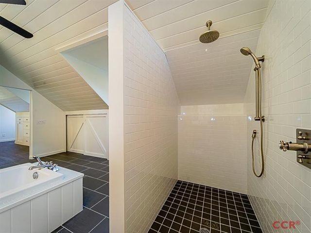 Cette image montre une grande salle de bain principale rustique en bois clair avec un placard à porte plane, une baignoire indépendante, un mur noir, un sol en carrelage de porcelaine, un lavabo encastré, un plan de toilette en quartz et un sol noir.