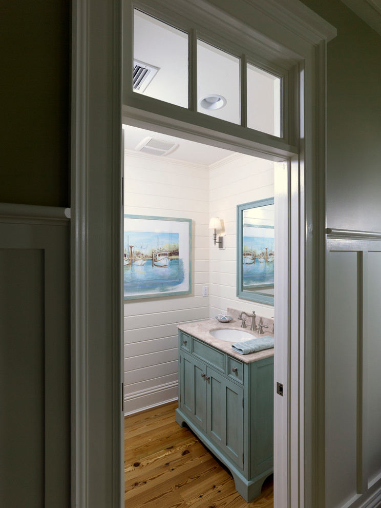 Cette photo montre une salle de bain bord de mer de taille moyenne avec un lavabo encastré, un placard à porte shaker, des portes de placard turquoises, un plan de toilette en marbre, un carrelage blanc, des carreaux de céramique, parquet clair, un mur blanc et un sol marron.
