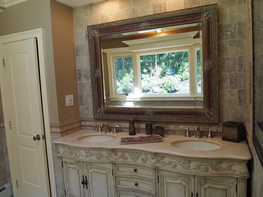 Example of a mid-sized tuscan master brown tile and ceramic tile alcove shower design in New York with raised-panel cabinets, distressed cabinets, brown walls, an undermount sink, limestone countertops and beige countertops